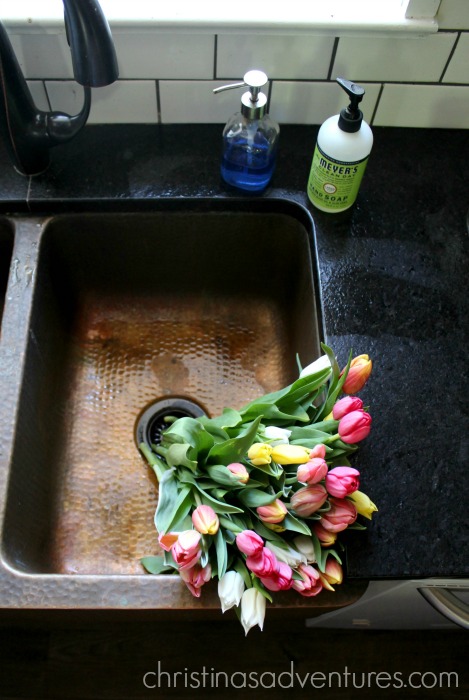 tulips in a copper sink with black leathered granite countertops