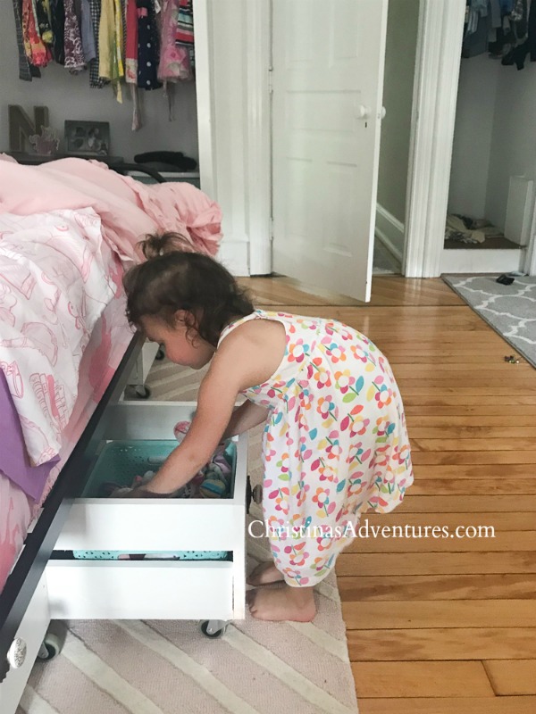 toddler putting clothes away in under bed storage drawers